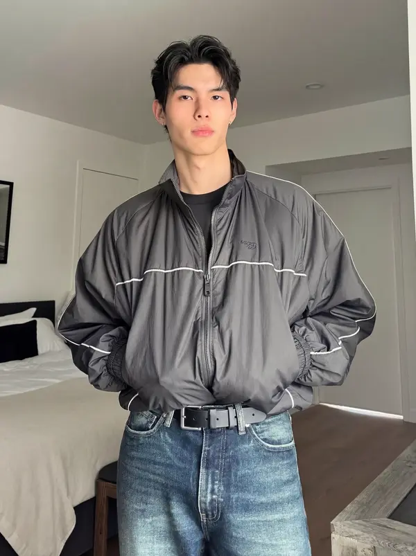 AI actor Jin in a grey track jacket in a bedroom, from Pixraft Marketing Studio